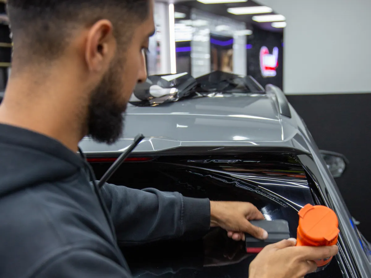 Tint film being squeegeed onto the rear window of an Audi RS Q3